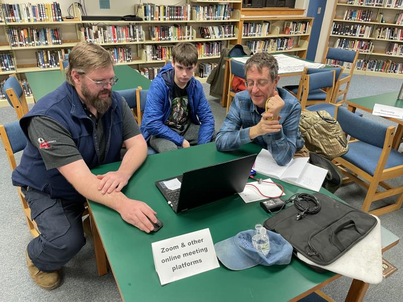 Brandon Look, a digital planner with Coastal Maine Regional Broadband , left, and BRHS student Cole Hyson, help a community member move content from an old device to a new one. Courtesy of Raye Leonard