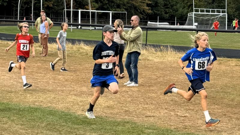 John Cooper, center, fights to pass the runner in front of him as they enter the finish tunnel. Courtesy of Barbara Crocker Boy runners