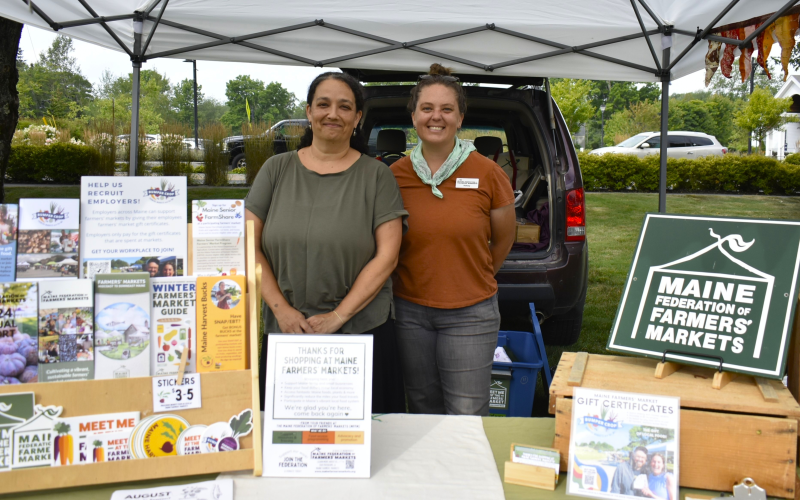 Jaime Berhanu and Kelsey Kobik of Maine Federation of Farmers' Markets make a local appearance to share information about their organization and celebrate its partnership with the Boothbay market. ISABELLE CURTIS/Boothbay Register Jaime Berhanu and Kelsey Kobik of the Maine Federation of Farmers' Markets make a local appearance to share information about their organization and celebrate its partnership with the Boothbay market. ISABELLE CURTIS/Boothbay Register