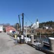 The Fish Pier of Boothbay Harbor. of Boothbay Harbor. The white and red buildings in the background on the left will be demolished and rebuilt when new construction begins. The crane in the foreground loads heavy barrels of bait onto waiting lobster boats. KATRINA CLARK/Boothbay Register