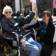Jean McVicker, of Boothbay Harbor, waves an American flag as she is lifted into a new St. Andrews Village bus May 13 with the assistance of Village Activities Director Jerie Phinney. Courtesy of Lincoln County Healthcare