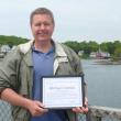 Local activist Mike Tomko stands on the footbridge in Boothbay Harbor with his award. “I’m very pleased that the selectmen and town manager of Boothbay Harbor have been talking about the footbridge improvement project,” Tomko said. “It’s such an iconic part of our town and can be a much bigger draw than it currently is.” KATRINA CLARK/Boothbay Register