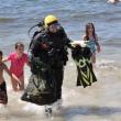 Young beach-goers swarm around Brian Boone as he returns with a bag full of sea creatures and other found items. From a 45-minute dive, Boone culled squid eggs, a juvenile lobster, several hermit crabs, a golf ball, a quahog and one feisty rock crab from the waters off Pemaquid Beach. BEN BULKELEY/Boothbay Register