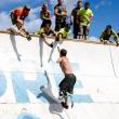 Wounded warrior Noah Galloway soars up “Everest” as Jason Nein (left) and Jared Mitkus (with mohawk) reach down to help him over. Karen Colby stands directly behind Mitkus. Courtesy of Tough Mudder photographer, Dmitry Gudkov.