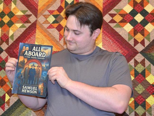 Author Samuel Hewson with an artificial intelligence mock-up of the cover for his book first "All Aboard" a time travel adventure.  Eleanor Busby photo