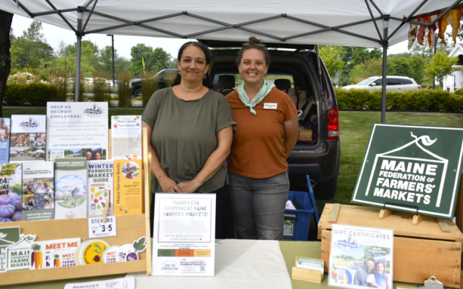 Jaime Berhanu and Kelsey Kobik of the Maine Federation of Farmers' Markets make a local appearance to share information about their organization and celebrate its partnership with the Boothbay market. ISABELLE CURTIS/Boothbay Register
