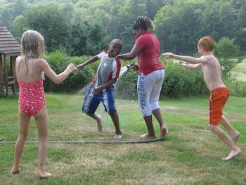 Tyrese, 10, from the Bronx, N.Y., second from left, and Reanna, 12, from Brooklyn, N.Y., third from left, have fun with a water hose during their visit with the Eve and Robert Conlin family in Boothbay.