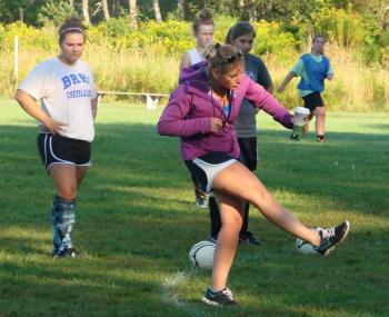 Soccer coach Kate Hossler demonstrates a strong and proper kick to the 17-member Lady Seahawks team at a recent practice. Below, Anna Baumm (left) and Brenna Alley vie for the ball during a scrimmage at the August 30 team practice. LISA KRISTOFF/Boothbay Register Soccer coach Kate Hossler demonstrates a strong and proper kick to the 17-member Lady Seahawks team at a recent practice.