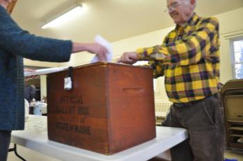 Donna Climo, left, puts ballots in the ballot box as Ronald Orchard, right, watches on Tuesday in Southport. BEN BULKELEY/Boothbay Register