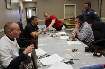 Left to right, BHPD Officer Scott Mercier, Chief Bob Hasch, Officer Jared Mitkus, Officer Nick Upham, and Sagadahoc Sheriffs Officer Detective Adam Temple. Below: Officer Mercier searches through some of the goods recovered from the Fuller residence at Boothbay Harbor Town Office March 28. Police have thousands of items to sort through and compare to individual itemized lists from area burglaries. SUE MELLO/Boothbay Register Left to right, BHPD Officer Scott Mercier, Chief Bob Hasch, Officer Jared Mitkus, Officer Nick Upham, and Sagadahoc Sheriffs Officer Detective Adam Temple. SUE MELLO/Boothbay Register