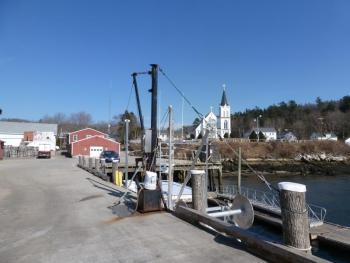 The Fish Pier of Boothbay Harbor. of Boothbay Harbor. The white and red buildings in the background on the left will be demolished and rebuilt when new construction begins. The crane in the foreground loads heavy barrels of bait onto waiting lobster boats. KATRINA CLARK/Boothbay Register