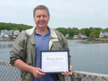 Local activist Mike Tomko stands on the footbridge in Boothbay Harbor with his award. “I’m very pleased that the selectmen and town manager of Boothbay Harbor have been talking about the footbridge improvement project,” Tomko said. “It’s such an iconic part of our town and can be a much bigger draw than it currently is.” KATRINA CLARK/Boothbay Register Local activist Mike Tomko stands on the footbridge in Boothbay Harbor with his award. “I’m very pleased that the selectmen and town manager of Boothbay Harbor have been talking about the footbridge improvement project,” Tomko said. “It’s such an iconic part of our town and can be a much bigger draw than it currently is.” KATRINA CLARK/Boothbay Register