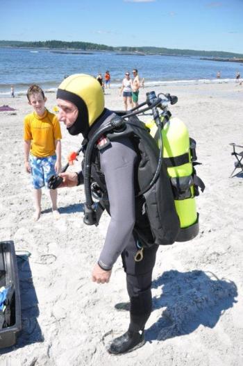 Geared up and ready to dive: Brian Boone, right, stands with almost all 130 pounds of his scuba on at Pemaquid Beach. BEN BULKELEY/Boothbay Register Geared up and ready to dive: Brian Boone, right, stands with almost all 130 pounds of his scuba on at Pemaquid Beach. BEN BULKELEY/Boothbay Register