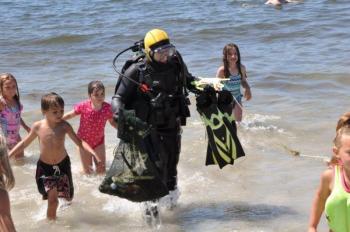 Young beach-goers swarm around Brian Boone as he returns with a bag full of sea creatures and other found items. From a 45-minute dive, Boone culled squid eggs, a juvenile lobster, several hermit crabs, a golf ball, a quahog and one feisty rock crab from the waters off Pemaquid Beach. BEN BULKELEY/Boothbay Register Young beach-goers swarm around Brian Boone as he returns with a bag full of sea creatures and other found items. From a 45-minute dive, Boone culled squid eggs, a juvenile lobster, several hermit crabs, a golf ball, a quahog and one feisty rock crab from the waters off Pemaquid Beach. BEN BULKELEY/Boothbay Register