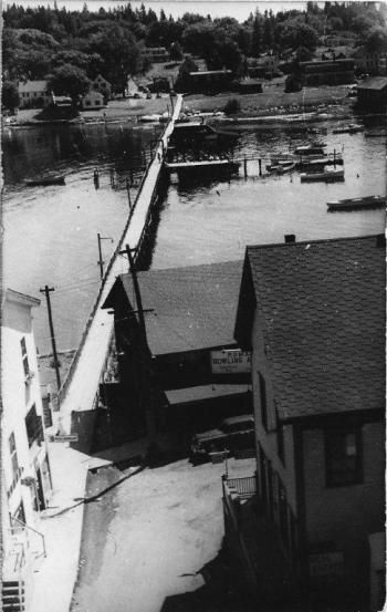 This mid-1900s shot is taken from the roof of the formerly taller and flat-roofed bank building in Bank Square. It looks east to the Romar Bowling Lanes run by Charlie Rowe, on the right, and the Blue Ship restaurant, run by his wife Kay Marr Rowe, on the left. The Romar name derives from combining Rowe and Marr. Across the footbridge, the little low building is the Bryan Rowe store. There is no good way to get a good view of the foreground buildings on their By-Way locations. Courtesy of Barbara Rumsey This mid-1900s shot is taken from the roof of the formerly taller and flat-roofed bank building in Bank Square. It looks east to the Romar Bowling Lanes run by Charlie Rowe, on the right, and the Blue Ship restaurant, run by his wife Kay Marr Rowe, on the left. The Romar name derives from combining Rowe and Marr. Across the footbridge, the little low building is the Bryan Rowe store. There is no good way to get a good view of the foreground buildings on their By-Way locations. Courtesy of Barbara Rumsey