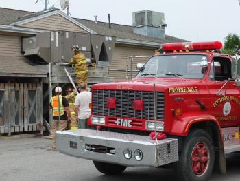 Boothbay firefighters inspect the malfunctioning air conditioner behind the gas station. RYAN LEIGHTON/ Boothbay Register