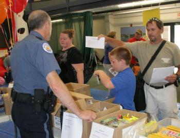 Boothbay Harbor Police Officer Larry Brown gets ready to help Dale Harmon and his son with the school supply list. KEVIN BURNHAM/Boothbay Register