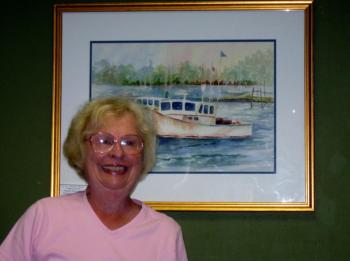 Virginia Forrest stands in front of her watercolor entitled "Boothbay Harbor Lobster Boats."