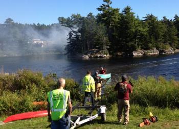 Firefighters wait on the mainland for a boat to be ferried out to the island in “The Marsh” in East Boothbay Saturday afternoon. JOE GELARDEN/Boothbay Register