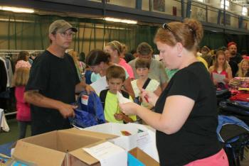Volunteer Heather Lorrain checks a list of school supplies for Derek Averill’s son. KEVIN BURNHAM/Boothbay Register