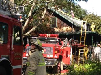 Boothbay Fire Chief Dick Spofford is called in for backup to a Bay Street chimney fire while crews scale the roof tops to clean the chimney. RYAN LEIGHTON/ Boothbay Register