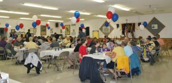 The Hometown Heroes crowd of about 100 people sits down to enjoy the meal of hamburgers and hot dogs. KEVIN BURNHAM/Boothbay Register