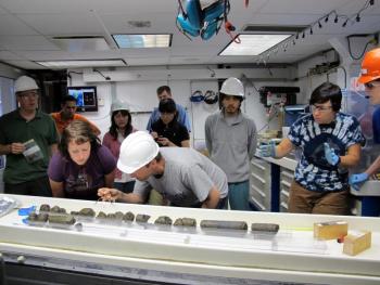 Dr. Beth Orcutt (front, second from left) of Bigelow Laboratory for Ocean Sciences examines oceanic crust samples with Dr. Wolfgang Bach of the University of Bremen, Germany, during IODP Expedition 336 to the Mid-Atlantic Ridge flank. Courtesy of Jennifer T. Magnusson