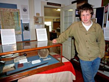 Devyn Campbell stands next to a glass case filled with Civil War artifacts he helped identify at the Boothbay Region Historical Society’s Civil War exhibit. KATRINA CLARK/Boothbay Register