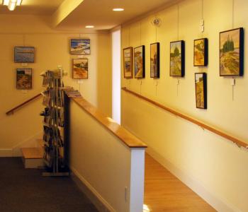 A WALKWAY lined with paintings of the present art show leads to one of the renovated rooms where groups meet. SUZI THAYER/Boothbay Register