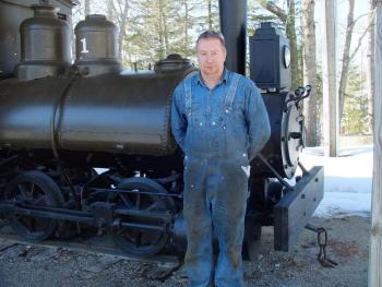 BRIAN FANSLAU of Alna stands in front of one the steam engines at the Boothbay Railway Village that is being made ready for the summer. SUZI THAYER/Boothbay Register