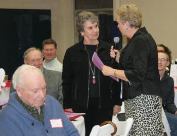 Sue Bradley, standing left, listens as outgoing Y board president Peggy Pinkham reads a list of contributions Bradley made to the board of trustees. KEVIN BURNHAM/Boothbay Register Bradley