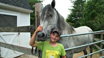 Young farmhand Wyatt Oakes with the largest horse, Necar, at Lyric Meadows Farm. KATRINA CLARK/Boothbay Register