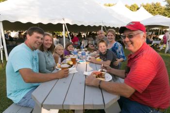 Dan Giles and family members gather at a picnic table during the pig roast on Saturday night on the Common. Courtesy of Michael Leonard