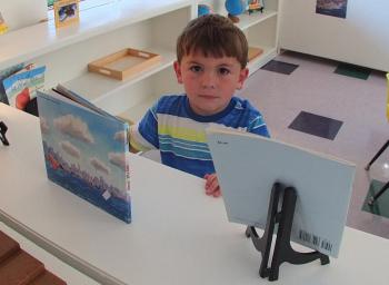 BYRAN HILLS looks over some of the books the new Montessori school has to offer. SUZI THAYER/Boothbay Register
