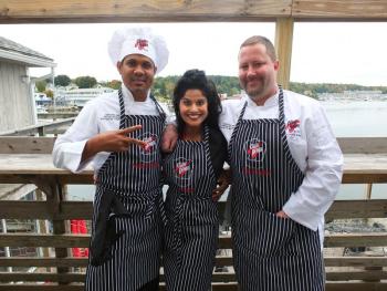 Chefs Dwayne Whitelocke and Steve Richards on the deck of Mine Oyster with their cheerleader and biggest fan, Boothbay Harbor Region Chamber of Commerce’s Cherie Scott. SUZI THAYER/Boothbay Register