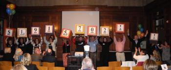 UNITED WAY CAMPAIGN CABINET members and Loaned Executives hold up signs revealing the total amount raised ($1,915,702) to the Campaign Finale audience. Courtesy of United Way