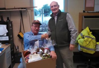PETER WILLIAMS presents the gift basket to John Orne at his Water District office on Tuesday morning. Courtesy of Peter Williams
