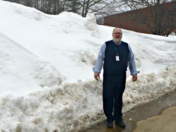 Boothbay Region Elementary School Principal Mark Tess stands outside where the entrance to the playground should be, where a snowbank taller than he is stands instead. KATRINA CLARK/Boothbay Register
