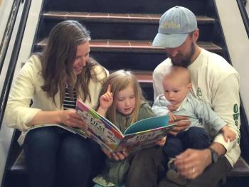 Enjoying a story as a family on the steps at the book fair. From left: Amy Redfern, Georgia, Shepherd and Shawn Griffith. KATRINA CLARK/Boothbay Register