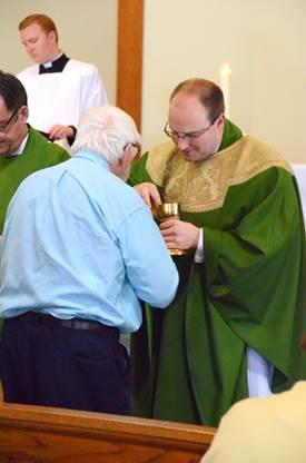 Father Steven Cartwright serves Communion to Henry Rowe. Courtesy of Lois Czerniak, Roman Catholic Diocese of Portland