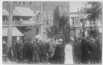 This view also may have been taken during the first Armistice Day parade on November 11, 1918, with onlookers looking down to Townsend Avenue from Oak Street next to the bank and the Townsend Hotel. A boy has again found something climbable!