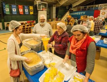 Tom Dewey and pastor Sarah Foulger of Boothbay Harbor's Congregational Church (center left and center right) on the assembly line at Sunday's "End Hunger in New England" event, a joint venture between the Boothbay Harbor Rotary and Damariscotta-Newcastle Rotary clubs to package food packets for needy area families. Courtesy of Steve Demeranville
