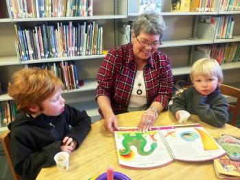 Mary Pinkham, with Camen, left, and Caleb Kearns, doing what she has loved doing for 29 years – reading to children at the Boothbay Harbor Memorial Library. SUZI THAYER/Boothbay Register