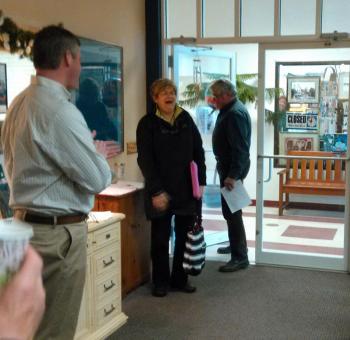Boothbay Town Manager Dan Bryer Jr., left, and Southport Selectman Gerry Gamage welcome a surprised Jane Good to her “thank you” party. JANE CARPENTER/Boothbay Register