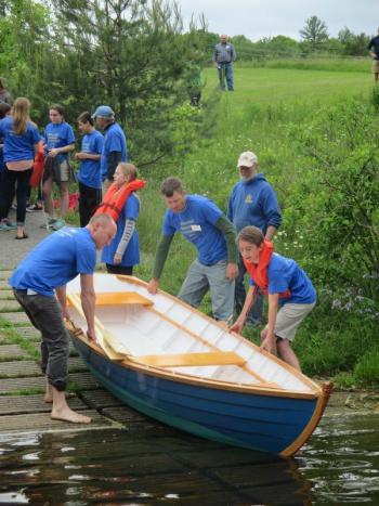 Kurt Spiridakis, Maine Maritime Museum boatshop manager and student advisor, is shown on the left lending a hand with the launch of one two skiffs built by Woolwich Central School seventh and eight graders. PHIL DI VECE/Wiscasset Newspaper
