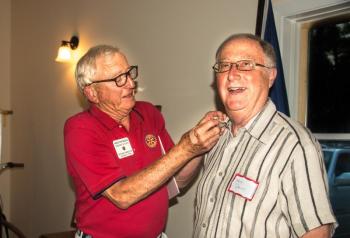 Outgoing club president Ham Meserve puts a Rotary pin on new member Fleet Davies. Courtesy photo