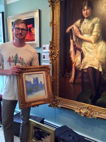 Ryan Hinton holds a painting, “New York City,” by Frederick Childe Hassam. The Fernand Toussaint.painting, “La Jeune Femme, is to his right. SUZI THAYER/Boothbay Register