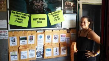 Reanna Heino of Two Salty Dogs Outfitters stands in front of the wall of fabulous prizes that will be won with raffle tickets at the 4th annual Mutt Scrub on July 30. Courtesy of Susan Reynolds