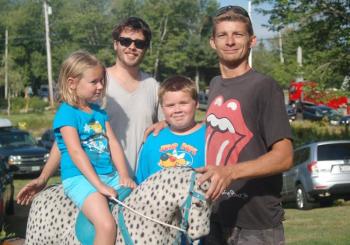 Makayla Abbe enjoys a hobbyhorse her family won at the auction. Pictured with her are Brian Abbe, Ben Abbe and Trevor Swope. ART MAYERS/Boothbay Register