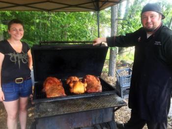 Christie and Travis Benner check on the smoked beef brisket and chicken that cooks all day behind their food stand. SUZI THAYER/Boothbay Register